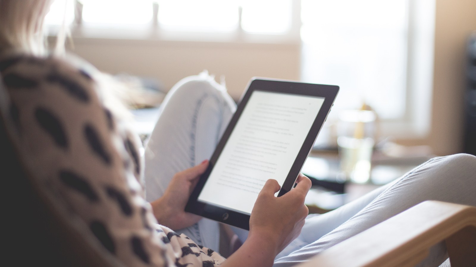 Una persona seduta che legge su un tablet.