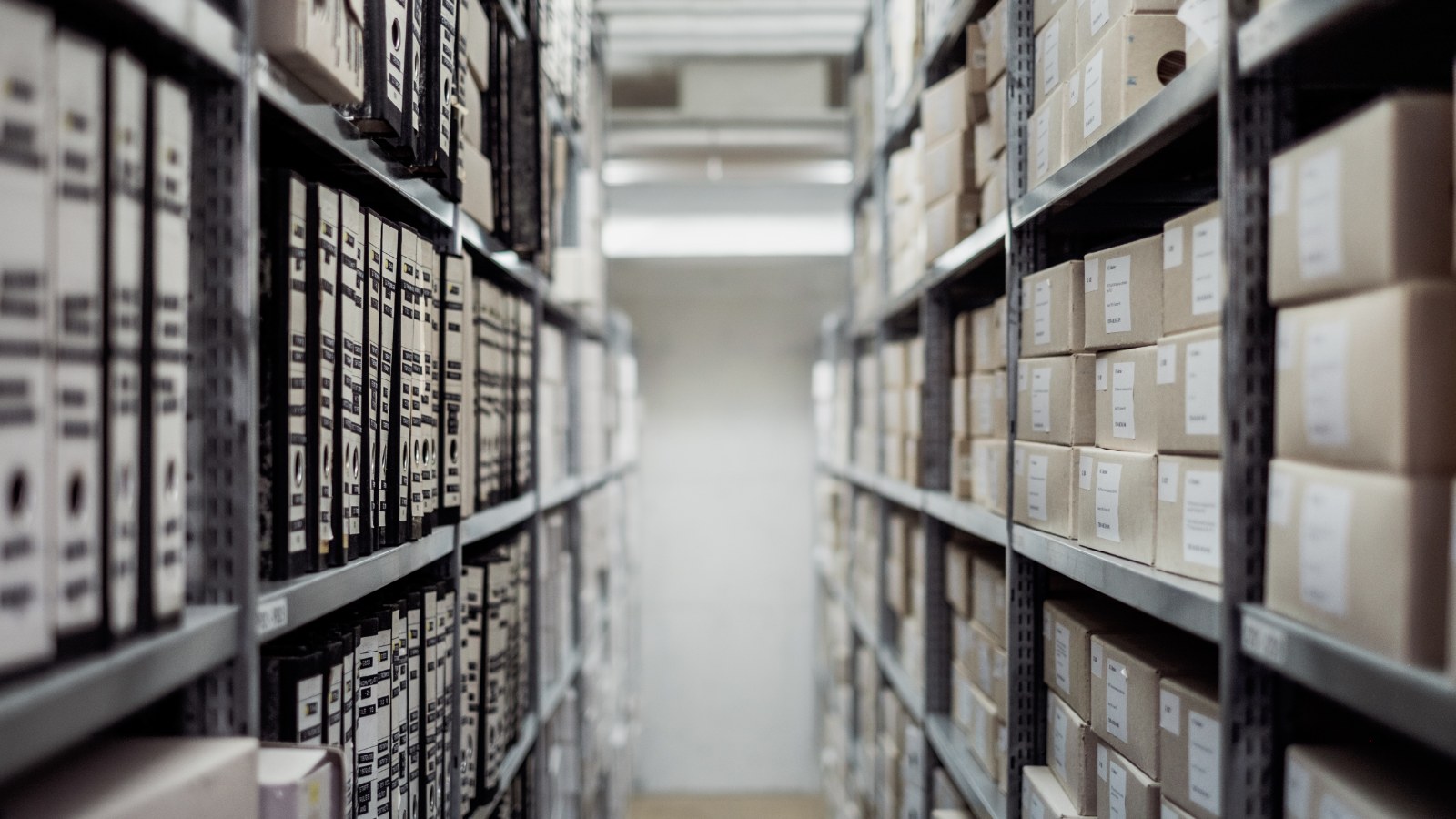 Scatole d'archivio e raccoglitori conservati su scaffali.